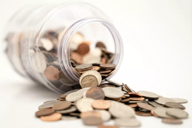 A tilted glass jar full of coins